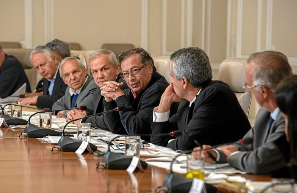 El presidente Gustavo Petro escucha atentamente durante una reunión de alto nivel junto a ministros y miembros de su gabinete de gobierno en una mesa de conferencias.