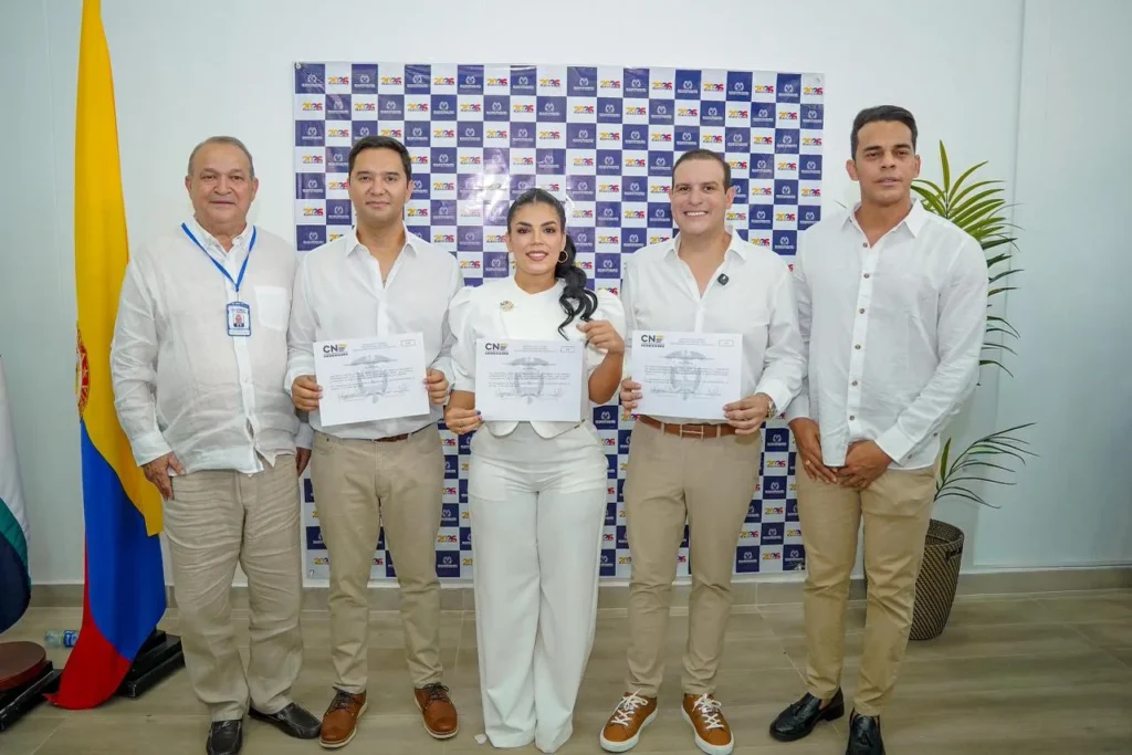 Grupo de nuevos representantes a la Cámara por el Cesar, incluyendo a Mello Castro y Gumer de la Peña, vestidos de camisa blanca y pantalón beige, mostrando sus credenciales del CNE. Destaca la ausencia de Ape Cuello.