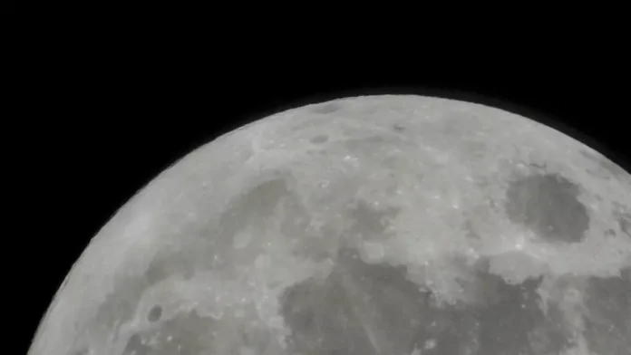 Primer plano del horizonte curvo de la Luna mostrando detalles de sus cráteres y mares de basalto sobre un fondo completamente negro, ilustrando la llegada de la misión Artemis II.
