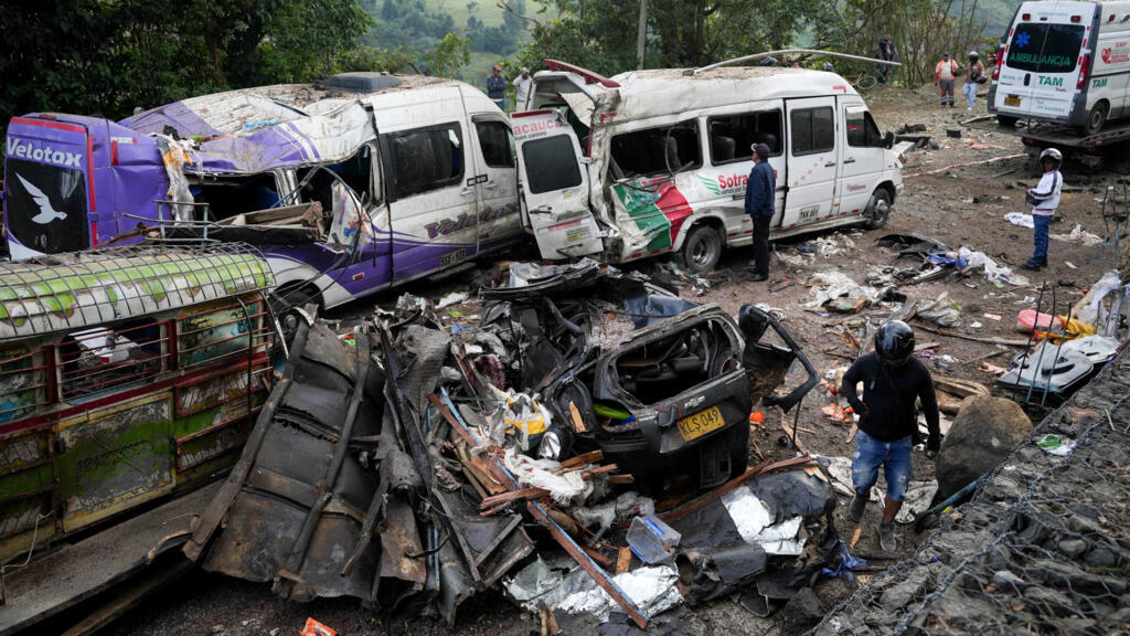 Expertos en explosivos inspeccionan los restos de una buseta escolar incinerada tras el atentado contra el Batallón Pichincha en el sur de Cali.