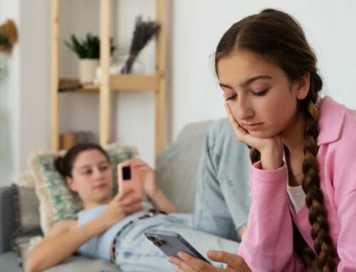 Una joven muestra señales de desinterés y aislamiento mientras usa su celular, ilustrando la importancia de la salud mental infantil.