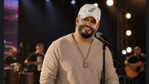 Fotografía de archivo del cantante de vallenato Nelson Velásquez sonriendo durante una presentación en vivo, sosteniendo un micrófono frente al escenario.