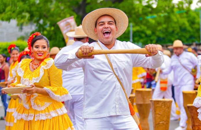 Grupo de piloneras bailando con trajes típicos amarillos durante el desfile del Festival Vallenato 2026 en Valledupar.
