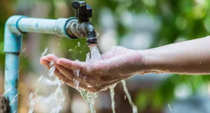 Persona usando agua de un grifo como referencia al cobro por uso de agua en el Cesar y su impacto en el acceso al recurso hídrico