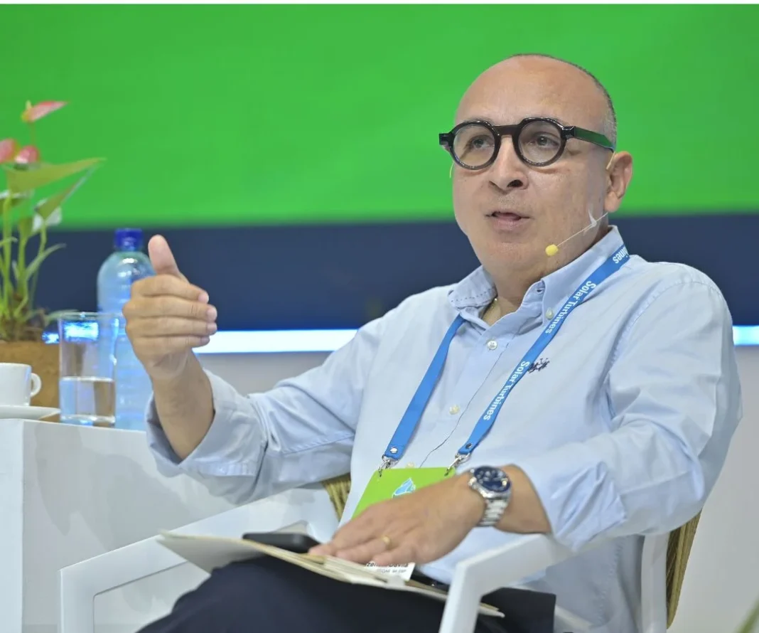 Retrato frontal de Carlos Mazeneth, Gerente General de Efigas, durante una presentación profesional. Viste una camisa azul claro, usa gafas de marco grueso y hace un gesto asertivo con la mano derecha.