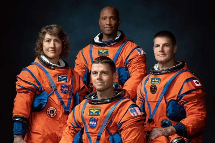 Fotografía de estudio de los cuatro astronautas de la misión Artemis II de la NASA posando con sus trajes espaciales de color naranja.