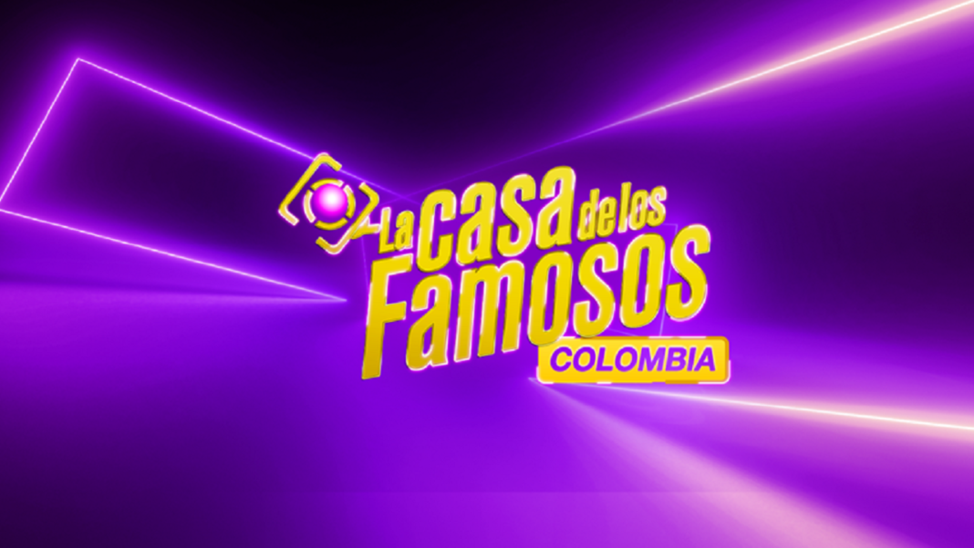 Logotipo oficial del programa de televisión La Casa de los Famosos Colombia, con letras gruesas amarillas y un ícono de lente de cámara, sobre un fondo de luces moradas de neón.