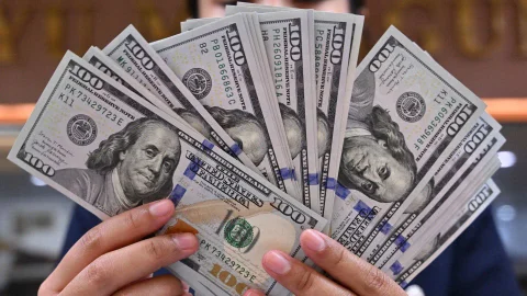 Una persona sostiene fajeados varios billetes de cien dólares estadounidenses ($100 US bills).