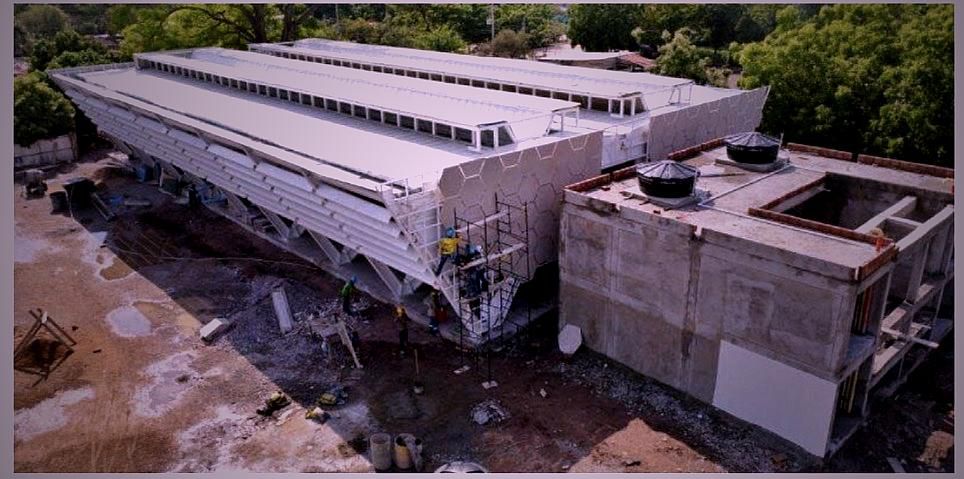 Vista aérea de una obra de construcción avanzada en Valledupar, mostrando una estructura moderna con fachada geométrica blanca y trabajadores en andamios.
