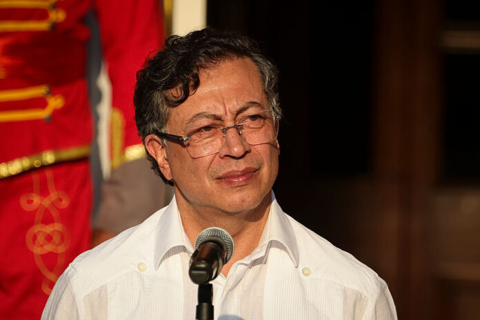 El presidente Gustavo Petro durante un evento protocolario frente a un micrófono, vistiendo guayabera blanca tradicional.