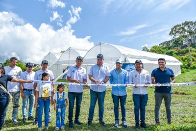 Autoridades y comunidad durante la inauguración de un invernadero agrícola con corte de cinta en zona rural
