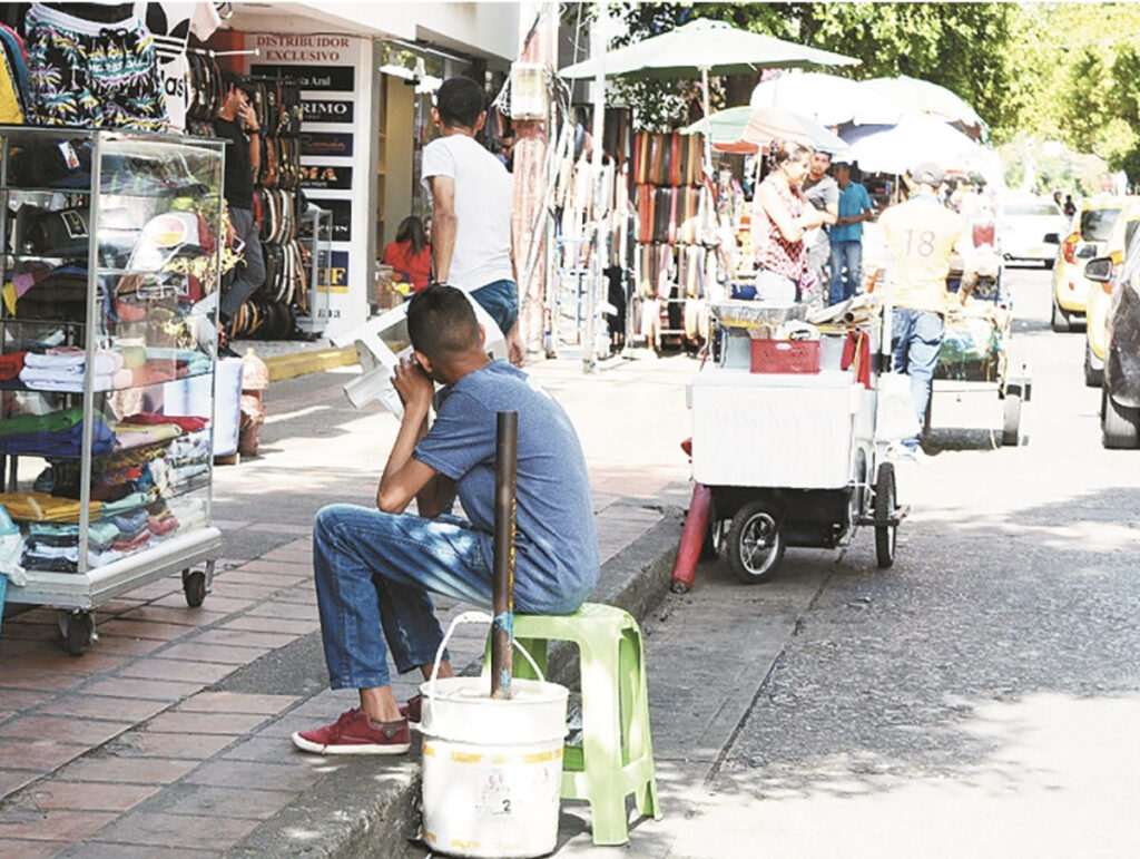 Joven sentado en una acera rodeado de ventas ambulantes, reflejo del aumento de la economía informal y el desempleo en el Cesar.