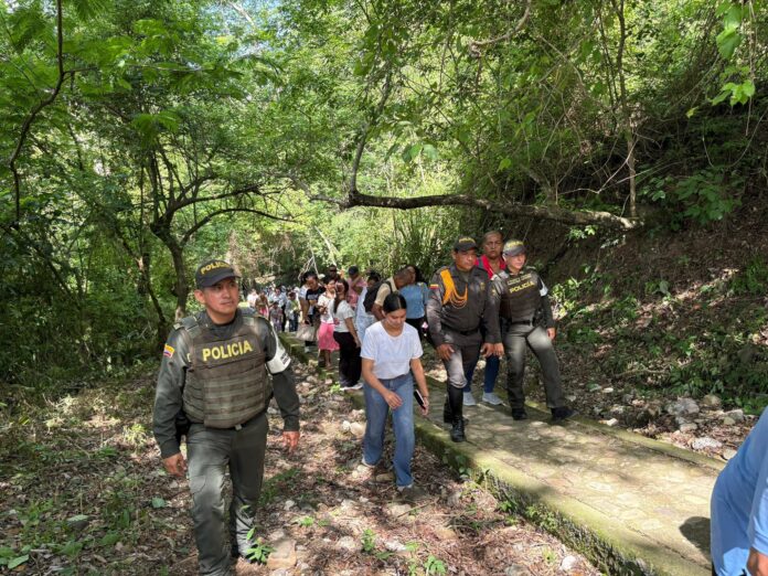 Uniformados de la Policía de Aguachica acompañan a feligreses en el sendero boscoso hacia el Cerro de la Cruz durante el Viacrucis.