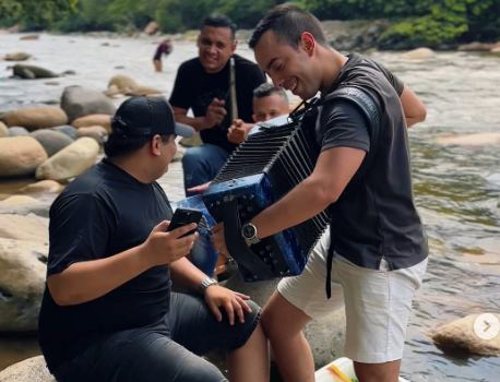 Grupo de músicos vallenatos anónimos interpretando el acordeón a orillas del río en Valledupar durante el festival.