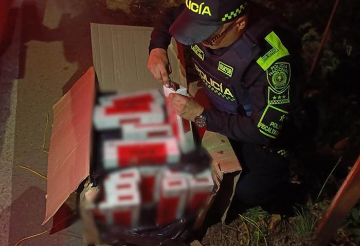 Un oficial de la Policía inspecciona cajas con cigarrillos de contrabando hallados en un bus en el Cesar.