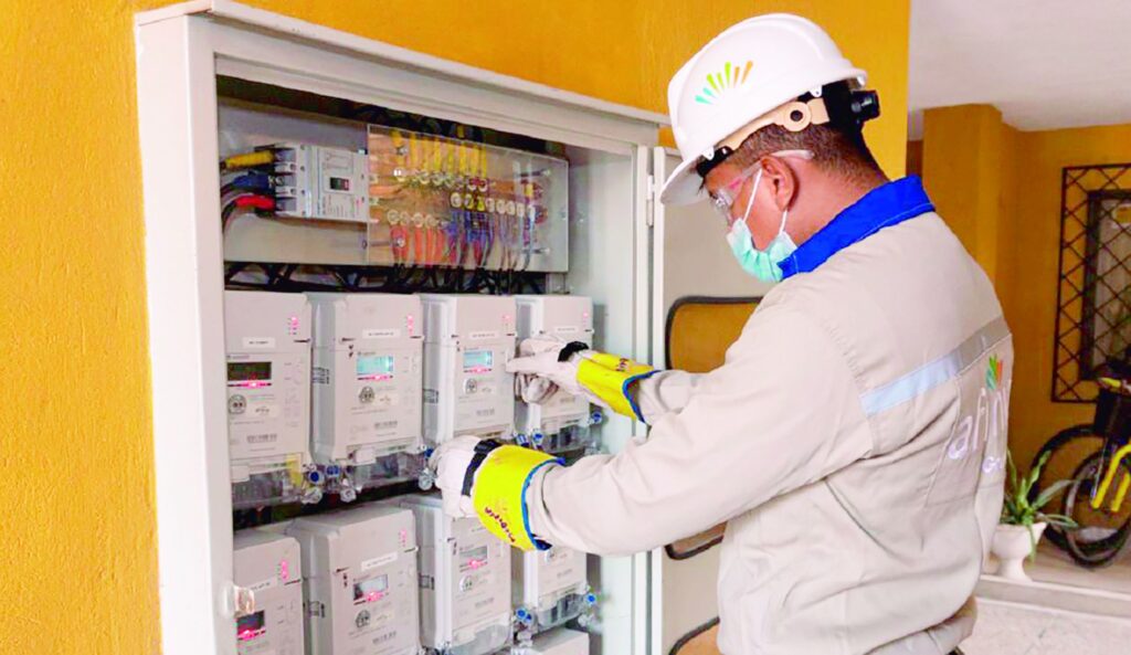 Un técnico de Afinia con casco y guantes revisa cuidadosamente los medidores digitales en un panel eléctrico.