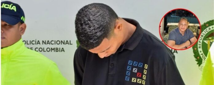 Un agente de la Policía Nacional custodia al presunto asesino de El Mono Estrada junto a un recuadro con la foto de la víctima.
