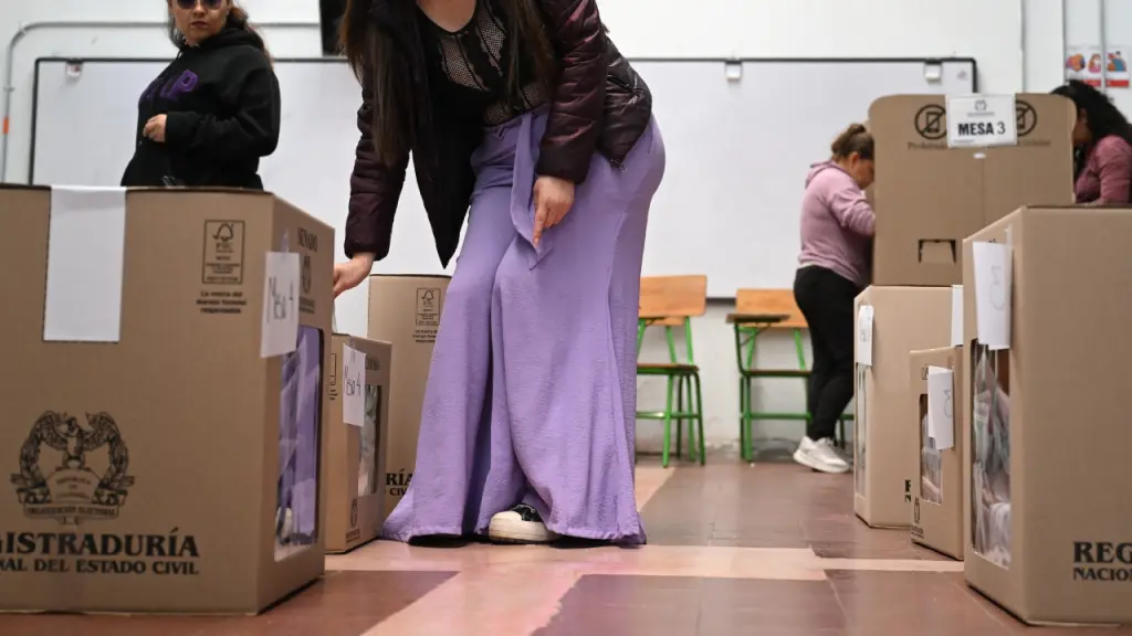Mujeres colombianas depositando sus votos en las urnas de la Registraduría Nacional durante una jornada electoral en un recinto cerrado.