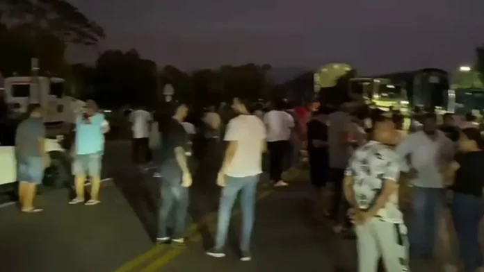 Grupo de ciudadanos bloqueando una carretera nacional en el Cesar de noche con camiones detenidos de fondo.