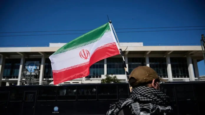 Estados Unidos ataca Irán: Hombre de espaldas ondeando la bandera iraní en medio de la creciente tensión internacional.