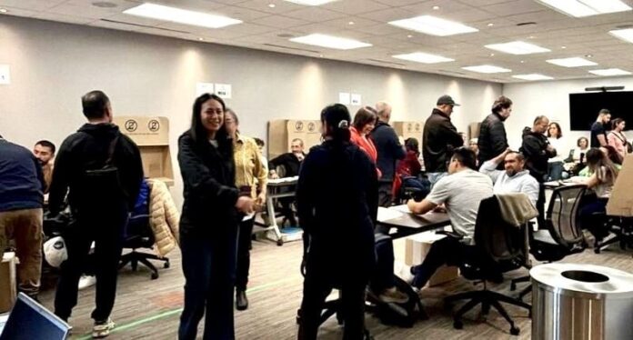 Ciudadanos asisten al puesto asignado para las votaciones en el exterior elecciones presidenciales dentro de una sede consular iluminada.