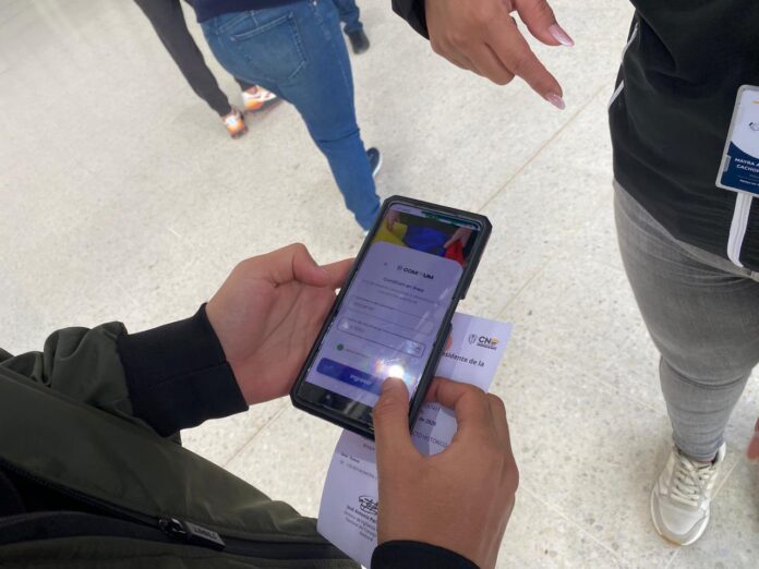 Persona verificando su acreditación como testigo electoral del CNE en un teléfono celular durante las elecciones en el exterior.