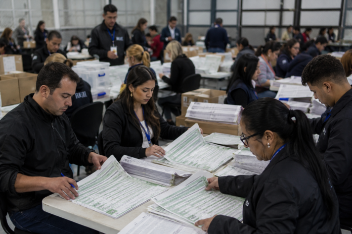 Funcionarios revisan formularios y resultados durante el proceso de escrutinio electoral en Colombia.