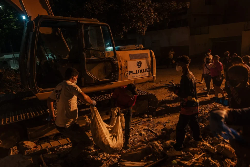 Voluntarios retiran escombros durante labores nocturnas tras los terremotos en Venezuela