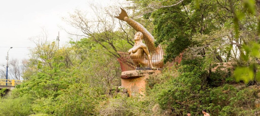 Monumento de la Sirena del Guatapurí rodeado de vegetación en el balneario Hurtado.