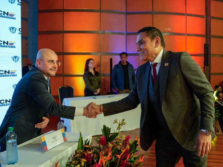 Dos dirigentes se saludan durante un evento del Consejo Nacional Electoral en Colombia