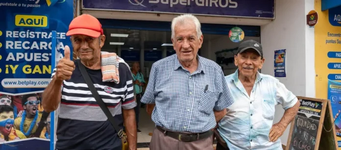 Adultos mayores frente a un punto de SuperGIROS después de reclamar el subsidio de Colombia Mayor