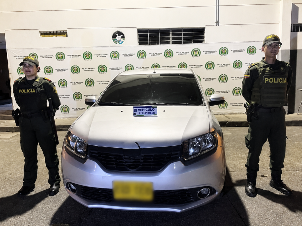 Dos uniformados de la Policía Nacional custodian un vehículo recuperado durante un operativo en Colombia.
