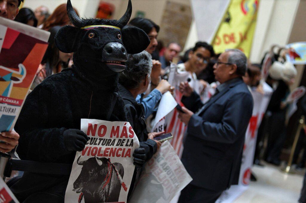 Manifestante disfrazado de toro sostiene un cartel contra la violencia en una protesta antitaurina en Colombia.