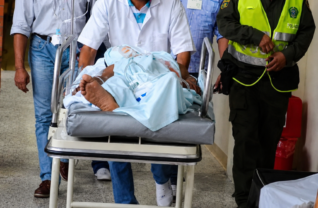 Paciente es trasladado en camilla a un centro asistencial bajo atención médica y acompañamiento policial.