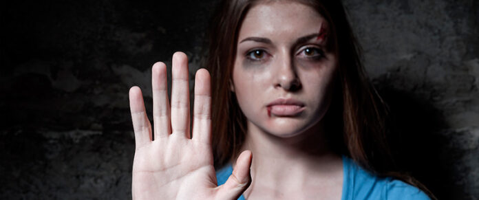 Mujer con señales visibles de agresión levanta la mano para rechazar la violencia de género