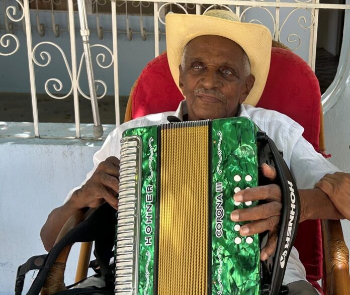 Náfer Durán sostiene su acordeón verde en su vivienda de El Paso, Cesar