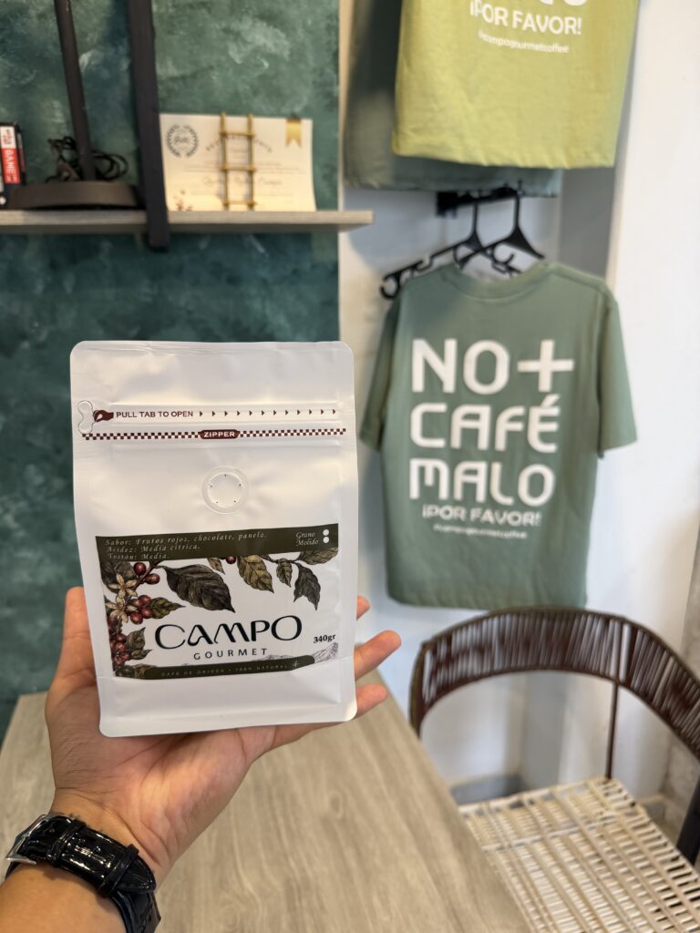 Primer plano de una bolsa blanca de café de especialidad de la marca Campo Gourmet, sostenida por una mano dentro de la cafetería en Valledupar.