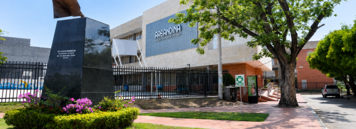 Fachada principal de la Universidad Areandina en Valledupar, destacando el edificio con el logo, un monumento oscuro en primer plano y jardines.