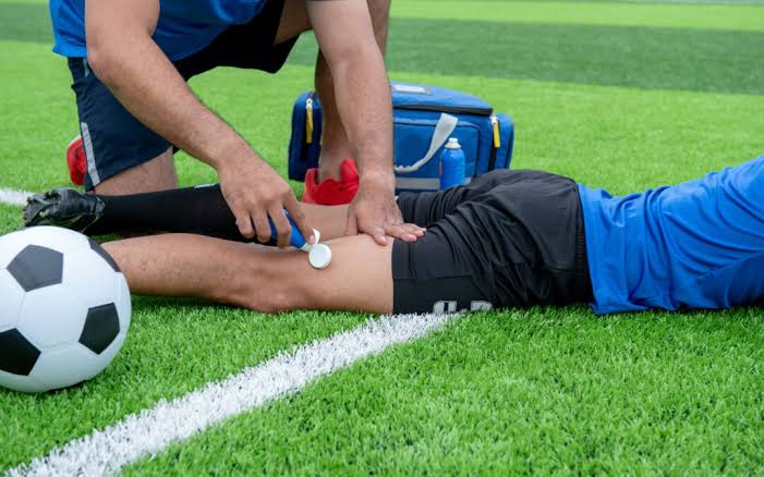 Personal médico atiende a un futbolista lesionado sobre el terreno de juego.