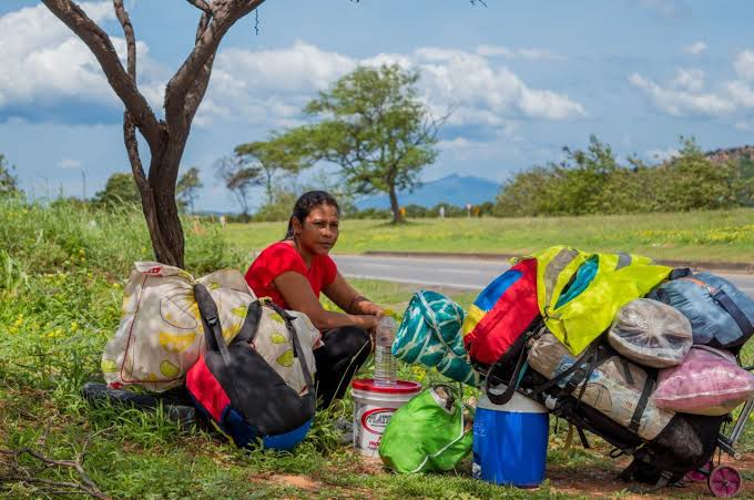 Migrante descansa junto a sus pertenencias en una carretera
