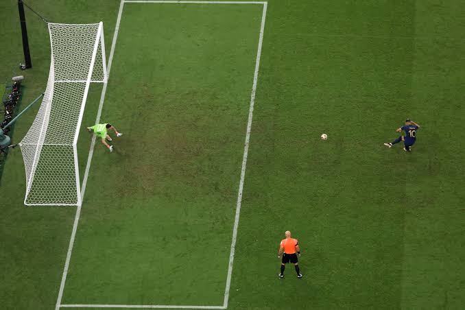 Futbolista ejecuta un penalti ante el portero y el árbitro.