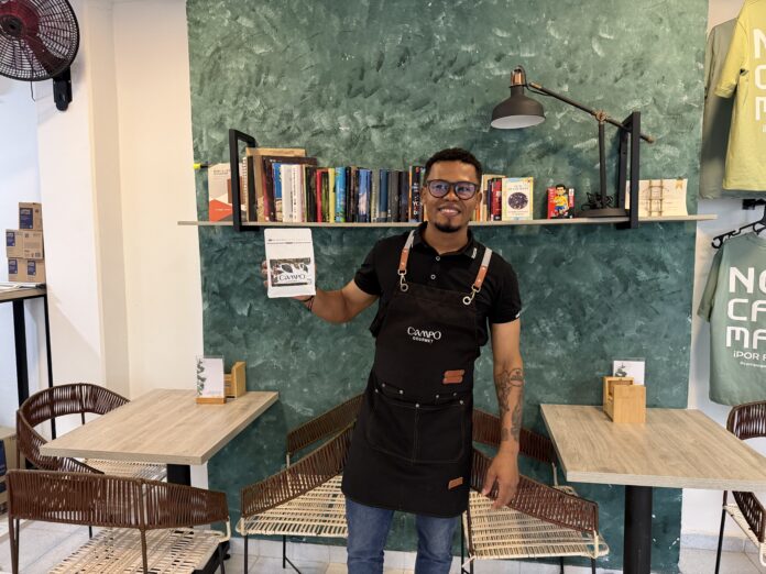 Rubén Campo, fundador de Campo Gourmet, sonriendo y sosteniendo una bolsa de café de especialidad dentro de su cafetería en Valledupar.