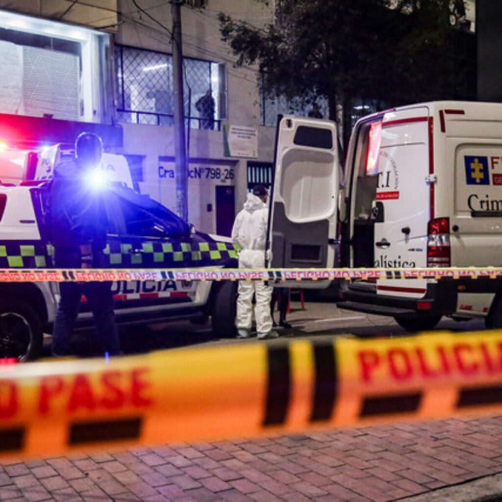 Policía y funcionarios forenses atienden una escena criminal durante la investigación de un doble homicidio.