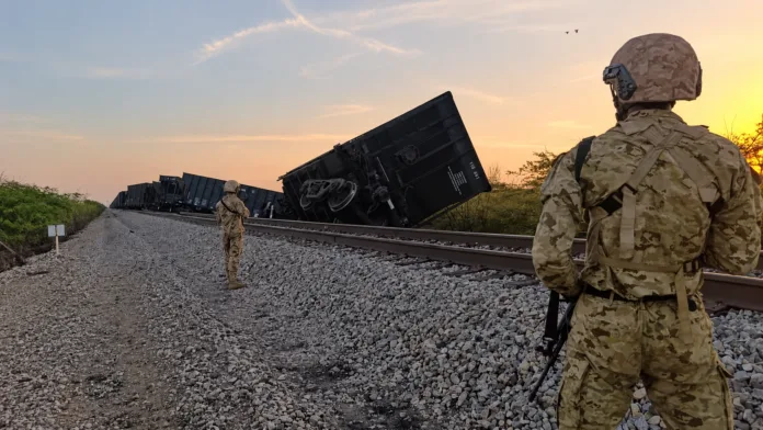 Soldados vigilan vagones volcados junto a la vía férrea del Cerrejón en Uribia, La Guajira.