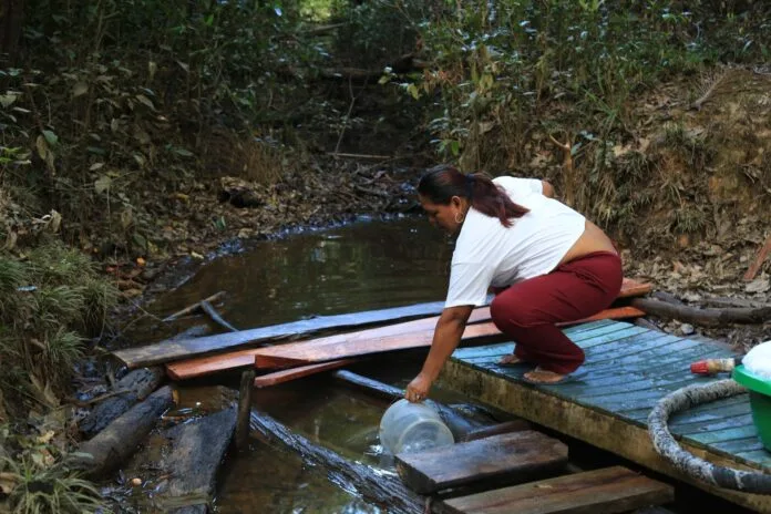 Mujer recoge agua de una fuente rural durante labores de abastecimiento