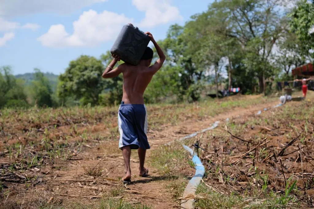 Menor transporta un recipiente con agua en una zona rural afectada por dificultades de abastecimiento