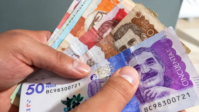 Persona sostiene billetes colombianos en medio del debate por el aumento del salario mínimo de 2027.