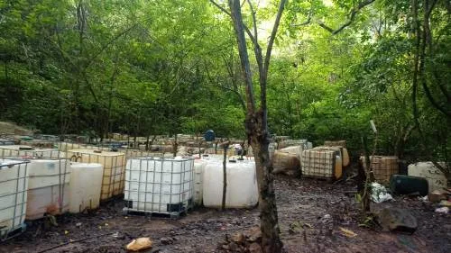 Contenedores plásticos y recipientes de almacenamiento en una zona boscosa, imagen del Ejército Nacional sobre hidrocarburos.