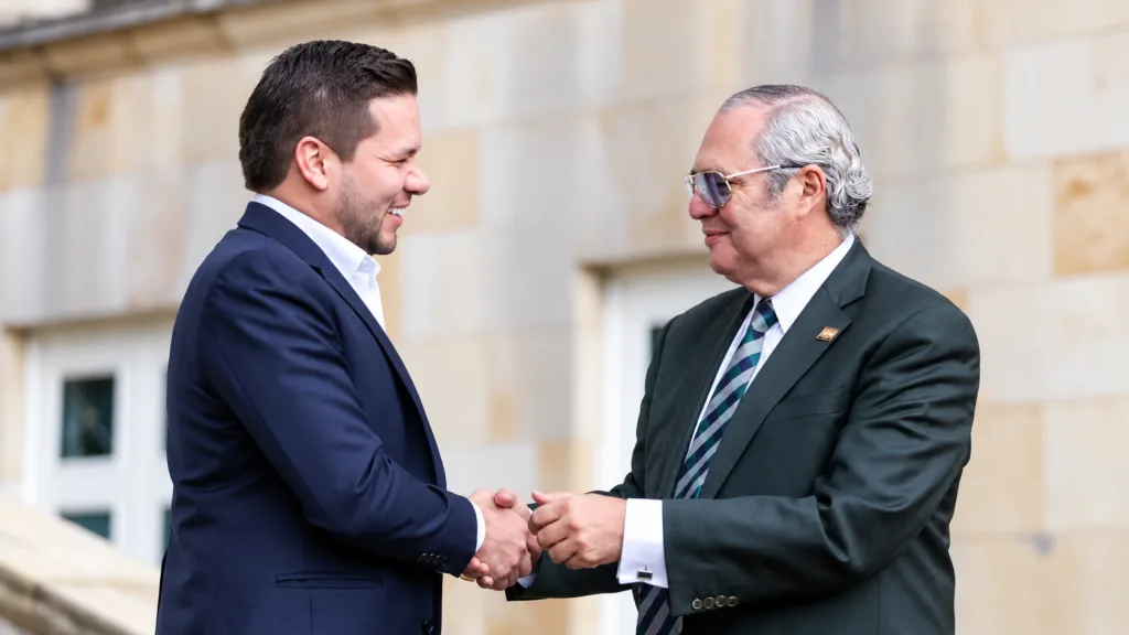 Iván Name y Andrés Calle se estrechan la mano en una imagen que acompaña la noticia sobre su libertad provisional en el caso UNGRD.