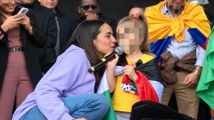 Niña con Mafe Carrascal en una tarima durante las marchas del 14 de octubre en Bogotá, con el rostro de la menor pixelado.